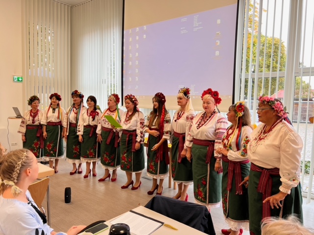 Ein ukrainischer Chor in traditioneller ukranischer Kleidung singt für das Publikum.  